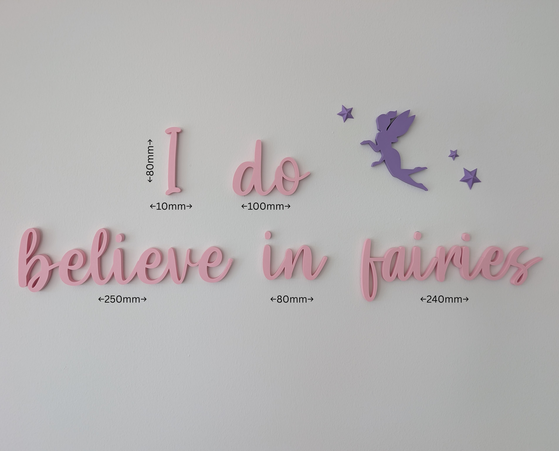 Decorative wall art with 'I do believe in fairies' text and a fairy silhouette on a light gray background.