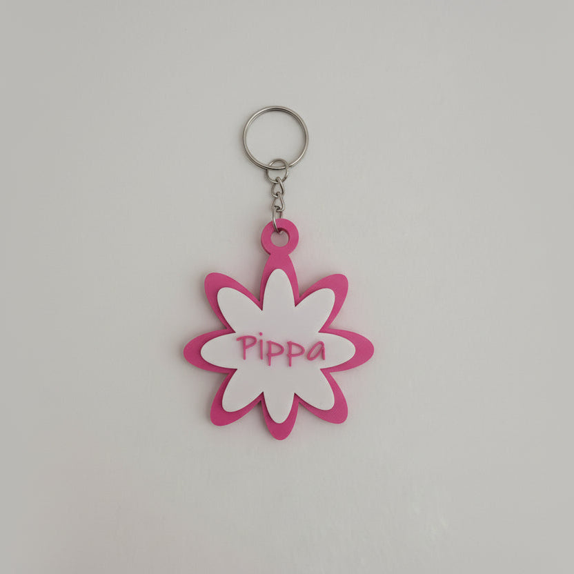Pink flower-shaped keychain with 'Pippa' on a white background
