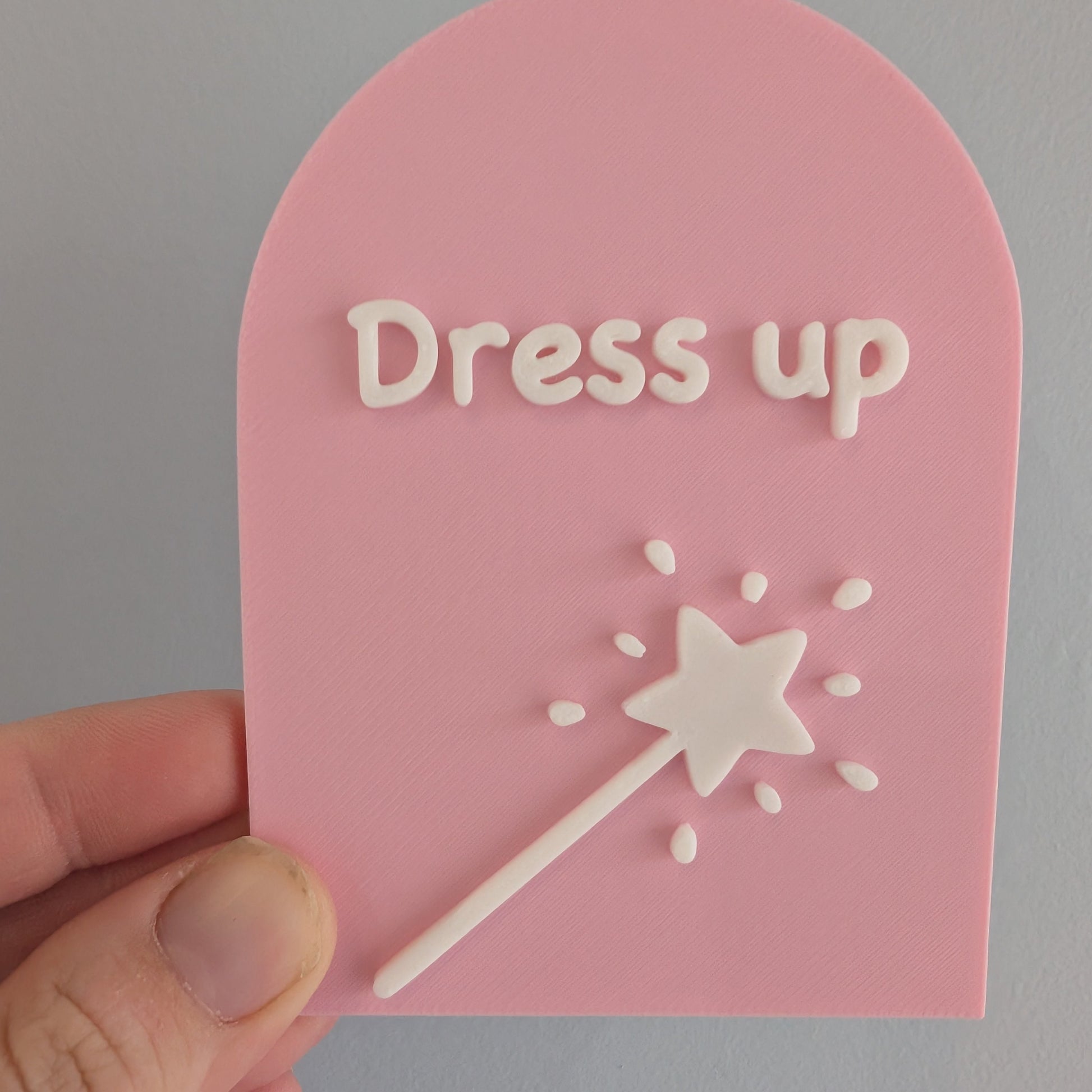 Pink card with 'Dress up' text and a white star wand on a gray background