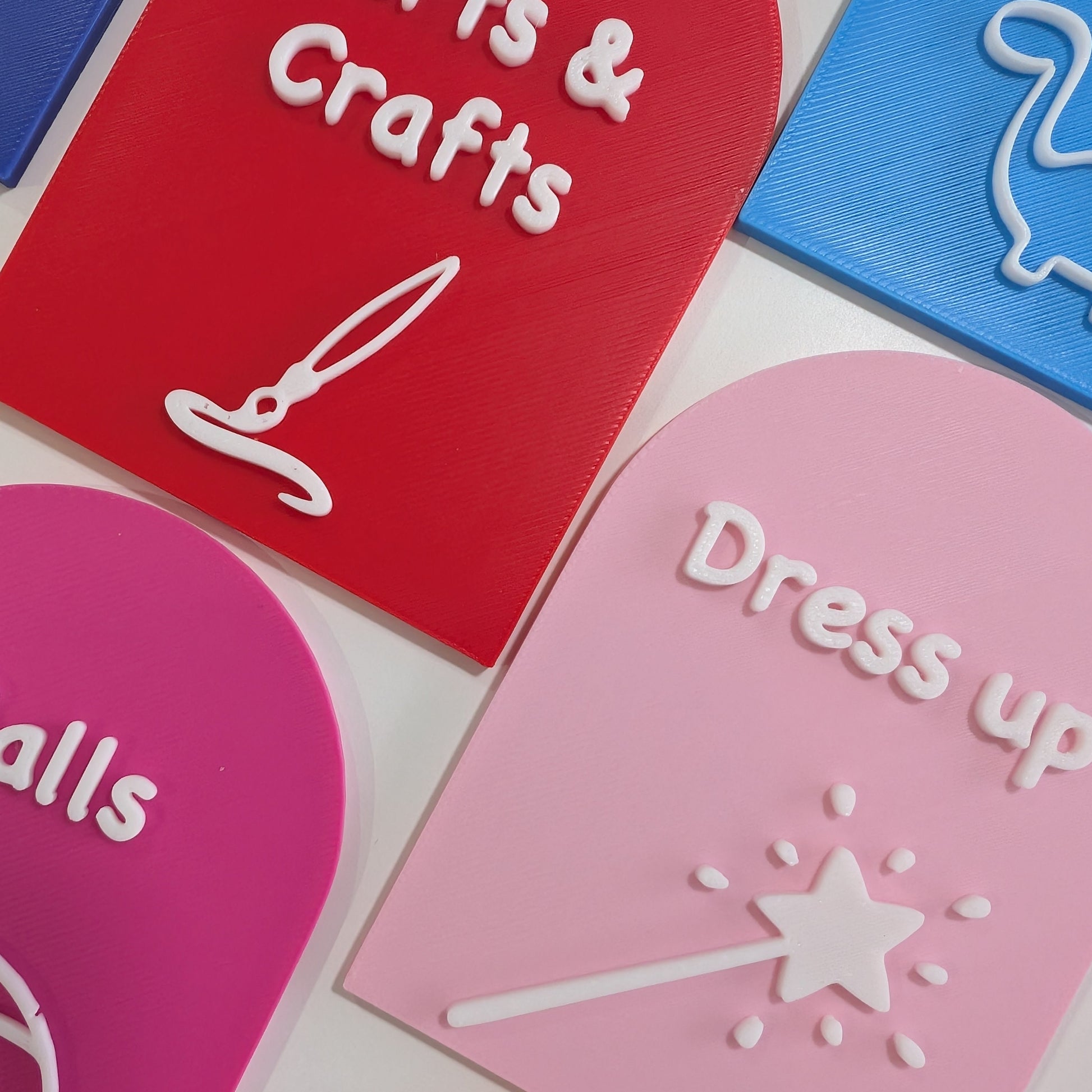 Colorful playroom labels for arts & crafts and dress-up areas on a white background.