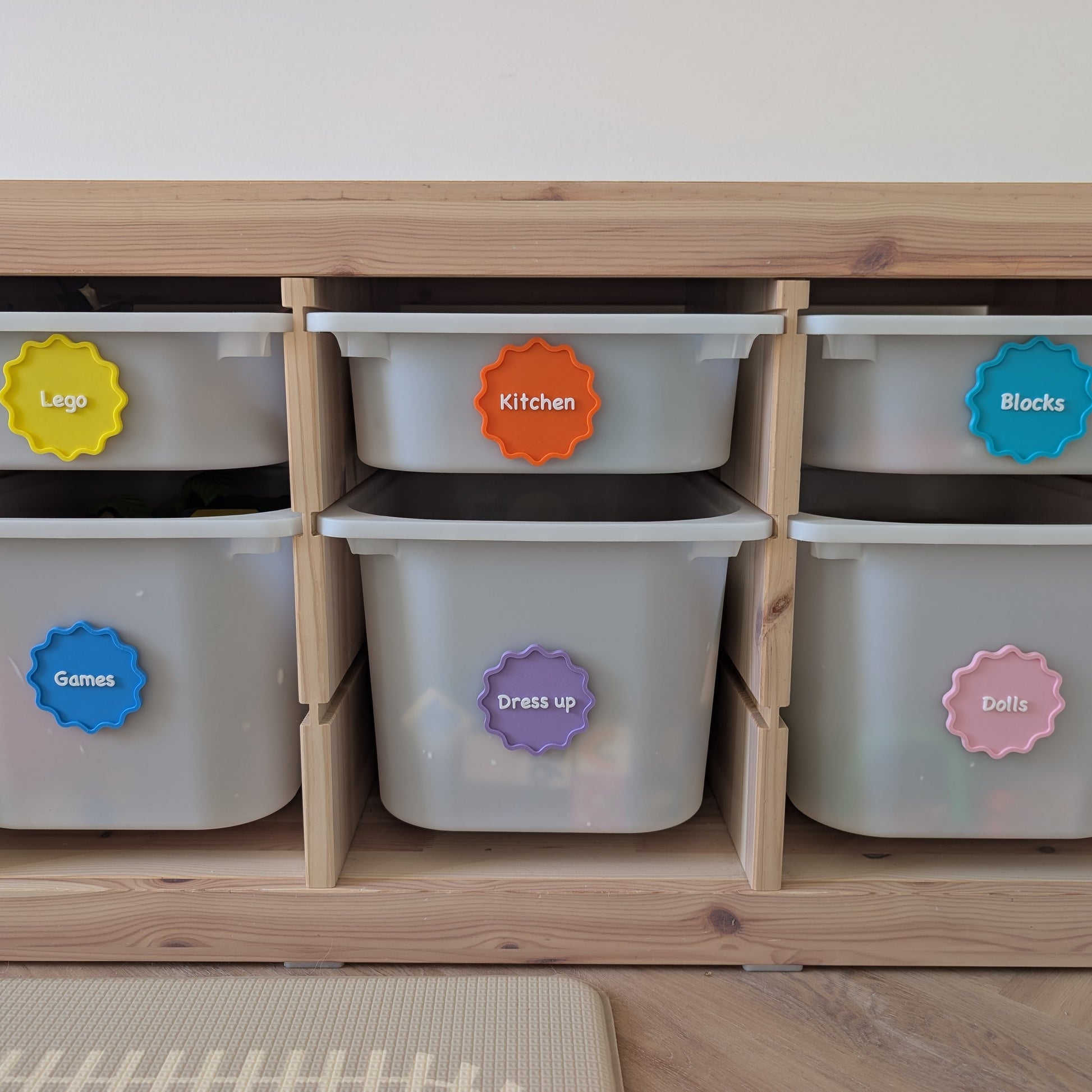 Wooden storage unit with labeled bins on a light wooden floor.