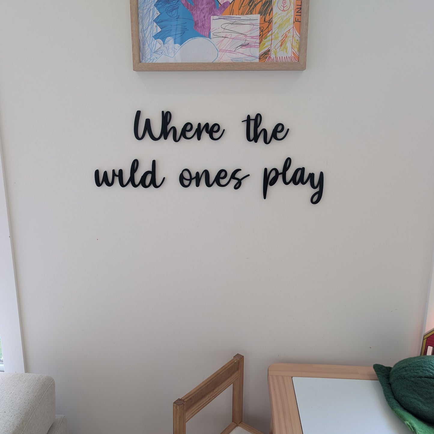 Children's artwork on a wall with 'Where the wild ones play' text